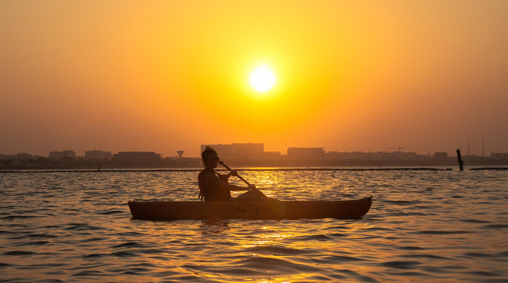  A person paddling a canoe on a calm body of water surrounded by trees
