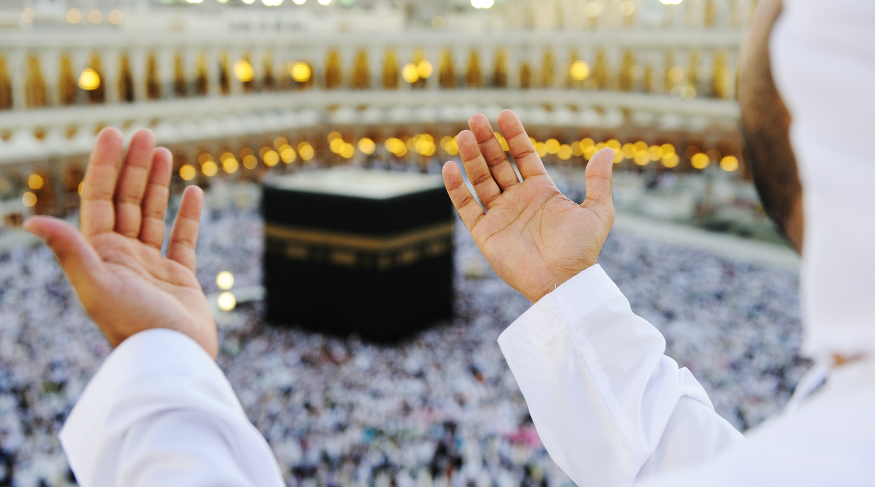 Man praying in front of the Kaaba, a sacred site in Mecca, Saudi Arabia, surrounded by worshippers.