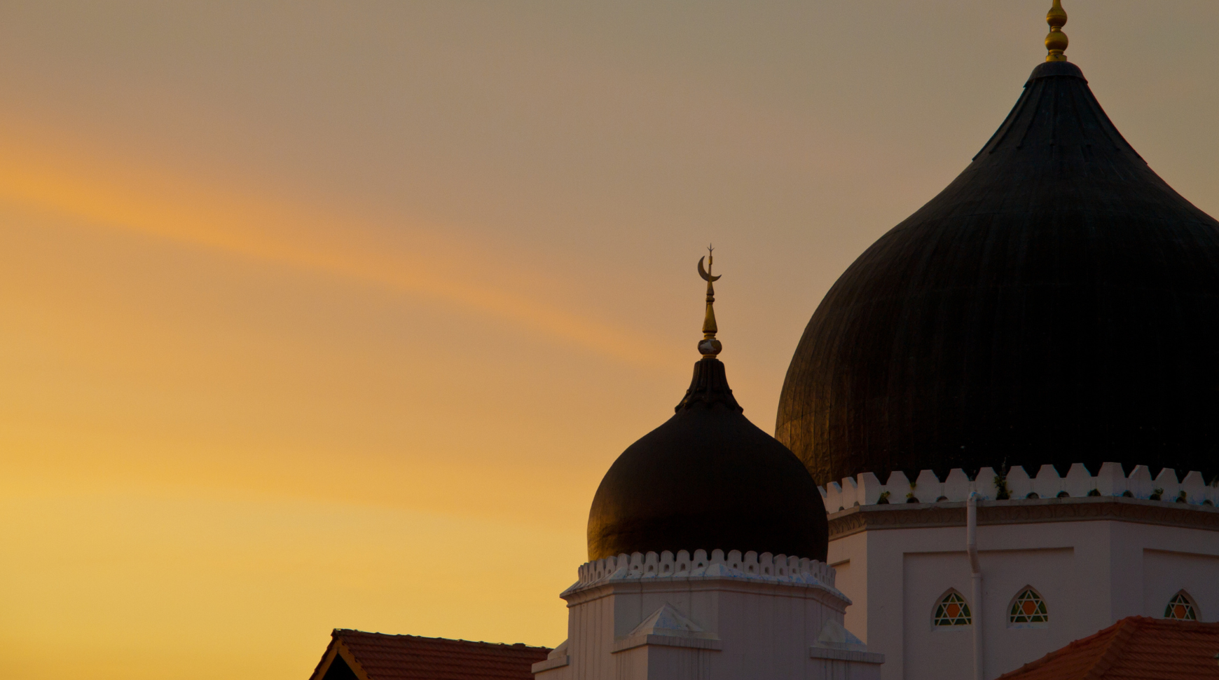 The sky is a vibrant orange, suggesting a sunset or sunrise with warm hues illuminating the atmosphere.